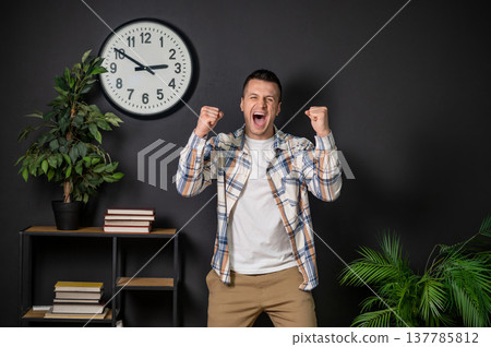 Excited man celebrating success with raised fists standing Excited man celebrating success with raised fists standing 137785812