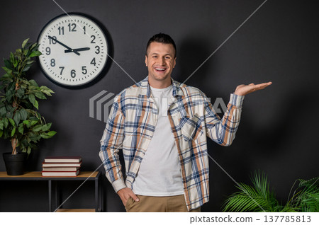 Cheerful man presenting something with hand standing in modern office interior Cheerful man presenting something with hand standing in modern office interior 137785813