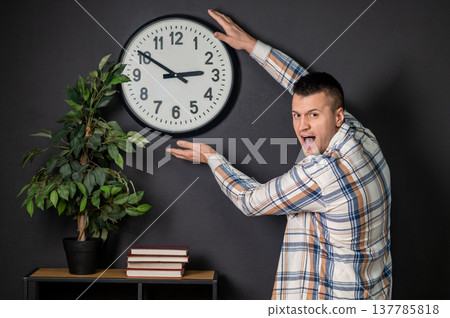 Surprised man presenting wall clock with hands Surprised man presenting wall clock with hands 137785818