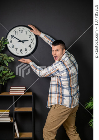 Shocked man presenting wall clock with hands Shocked man presenting wall clock with hands 137785819