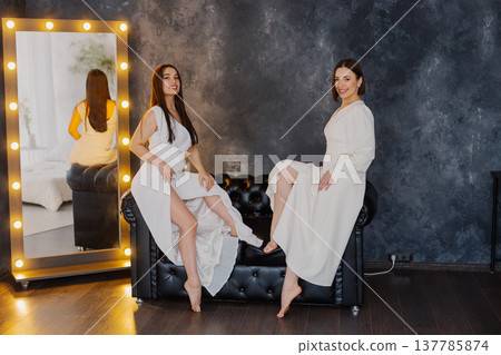 Two beautiful women on a leather sofa near a 137785874
