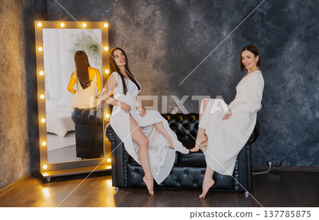 Two beautiful women on a leather sofa near a 137785875