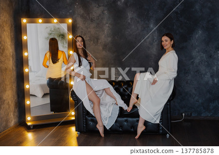 Two beautiful women on a leather sofa near a 137785878