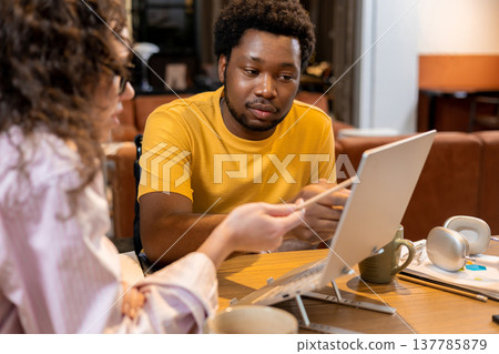 Woman and man colleagues collaborating on project on laptop in coworking space 137785879