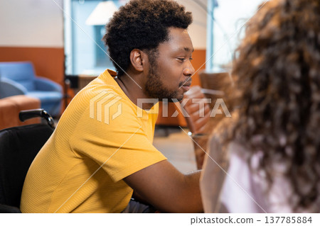 Man in wheelchair and woman colleague discussing online project Man in wheelchair and woman colleague discussing online project 137785884