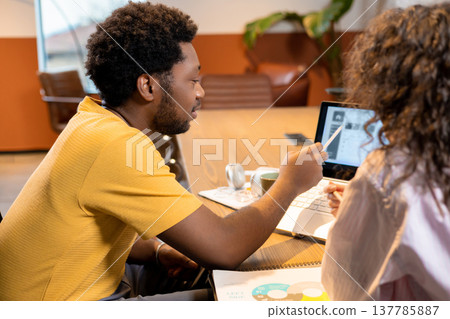 Man and woman colleagues discussing project using computer in coworking space Man and woman colleagues discussing project using computer in coworking space 137785887