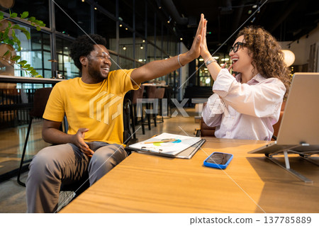 Professional man in wheelchair and woman high fiving celebrating project achievement Professional man in wheelchair and woman high fiving celebrating project achievement 137785889