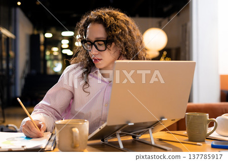 Young woman operating laptop computer in coworking environment 137785917