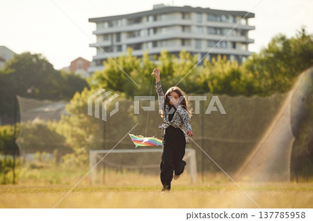 Kid is running, girl is playing with kite on the sunny field Kid is running, girl is playing with kite on the sunny field 137785958