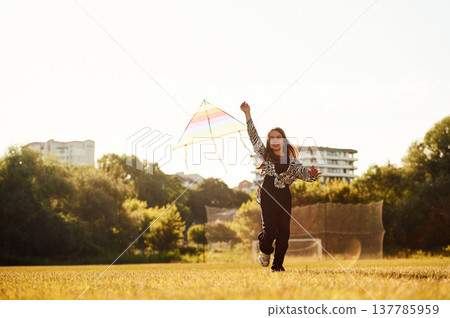 Kid is running, girl is playing with kite on the sunny field Kid is running, girl is playing with kite on the sunny field 137785959