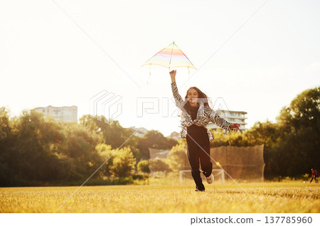 Kid is running, girl is playing with kite on the sunny field Kid is running, girl is playing with kite on the sunny field 137785960