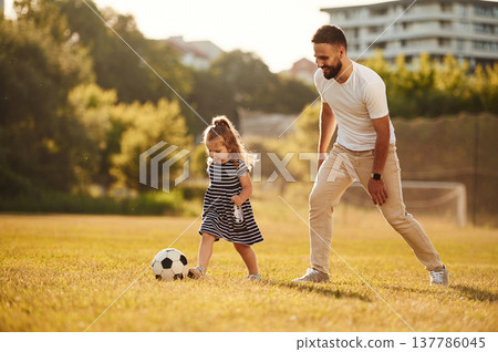 Playing soccer. Father with his little daughter are on the field 137786045