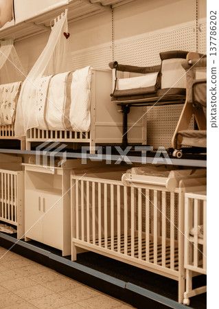 Shelves are filled with various types of baby cribs and bassinets. Parents browse the selection, seeking the right sleeping solutions for their children Shelves are filled with various types of baby cribs and bassinets. Parents browse the selection, seeking the right sleeping solutions for their children 137786202
