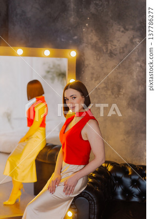 Young beautiful woman posing on leather sofa near Young beautiful woman posing on leather sofa near 137786277