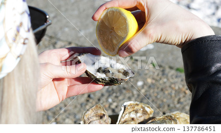A close-up of a girl squeezing lemon onto a fresh oyster A close-up of a girl squeezing lemon onto a fresh oyster 137786451