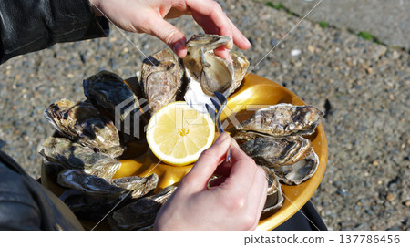 Close-up of a girl taking an oyster from a tray Close-up of a girl taking an oyster from a tray 137786456