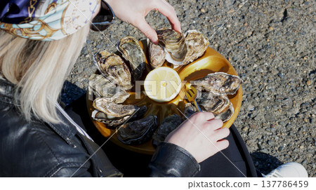 Close-up of a girl taking an oyster from a tray Close-up of a girl taking an oyster from a tray 137786459