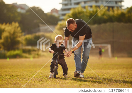 Teaching how to ride a bicycle. Happy father with son on the field 137786644