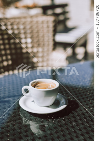 Cup of black coffee on a table in a street cafe. Selective focus. Cup of black coffee on a table in a street cafe. Selective focus. 137786720