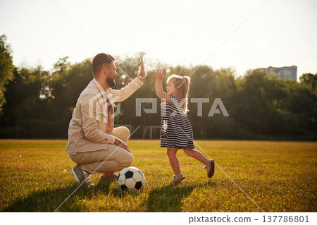 Great teamwork, high five, soccer players. Father with his little daughter are on the field Great teamwork, high five, soccer players. Father with his little daughter are on the field 137786801