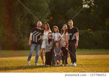 Looking forward. Family with adults and kids is standing on the field Looking forward. Family with adults and kids is standing on the field 137786852