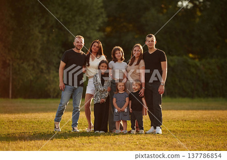Looking forward. Family with adults and kids is standing on the field Looking forward. Family with adults and kids is standing on the field 137786854