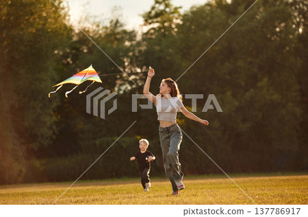 Sister and her little brother, with kite. Two kids are having fun on the summer field Sister and her little brother, with kite. Two kids are having fun on the summer field 137786917