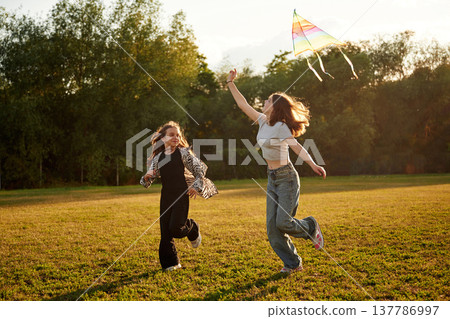 Two girls kids are playing with kite on the field Two girls kids are playing with kite on the field 137786997