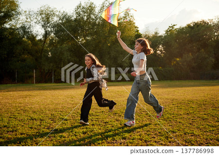 Two girls kids are playing with kite on the field Two girls kids are playing with kite on the field 137786998