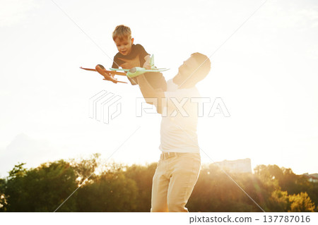 Against the white sky, with toy plane, flying. Happy father with son on the field 137787016