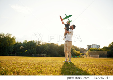 Against the white sky, with toy plane, flying. Happy father with son on the field 137787018