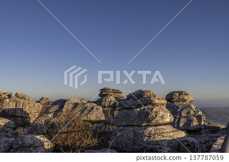 Rock formations in El Torcal Spain during sunset with clear sky and distant hills Rock formations in El Torcal Spain during sunset with clear sky and distant hills 137787059