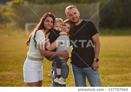 Green field, summertime. Photo of happy family with husband, wife and two kids Green field, summertime. Photo of happy family with husband, wife and two kids 137787068