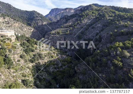 View of hills and valleys in Frigiliana, Spain during the daytime with clear skies and greenery present throughout the landscape View of hills and valleys in Frigiliana, Spain during the daytime with clear skies and greenery present throughout the landscape 137787157