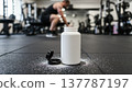 White protein supplement bottle with spill on gym floor, keys. Ideal for fitness, nutrition, clean, pre-workout, healthy, sports, gym, power, product, energy, strength. 137787197
