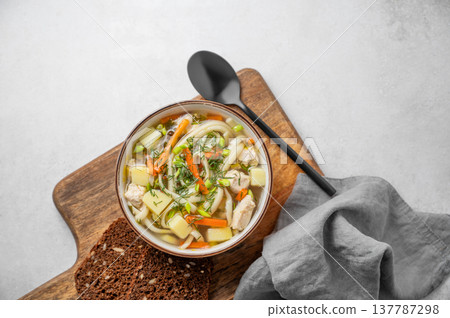 Chicken noodle soup with fresh dill in a bowl on a light textured background 137787298