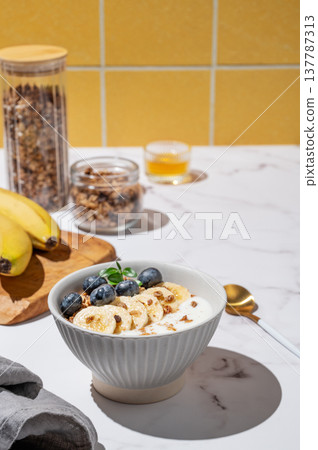Natural greek yogurt with granola, blueberry and banana in a bowl on a marble table 137787313