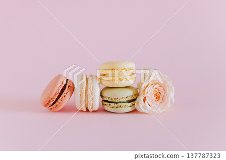 Tasty french macarons with tender rose flowers on a pink pastel background. Tasty french macarons with tender rose flowers on a pink pastel background. 137787323
