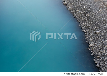 The blue surface of the Oi River and the gravel of the riverbank 137787509
