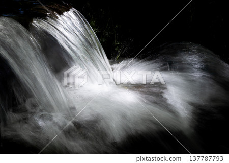 A fantastical stream of water emerges from the darkness. 137787793