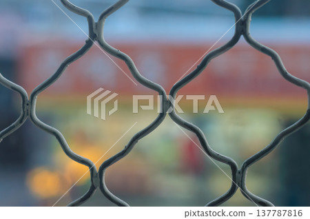 Chain-Link Fence Close-Up With Blurred Urban Background Chain-Link Fence Close-Up With Blurred Urban Background 137787816