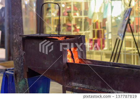 Metal charcoal grill with glowing embers at street market Metal charcoal grill with glowing embers at street market 137787819