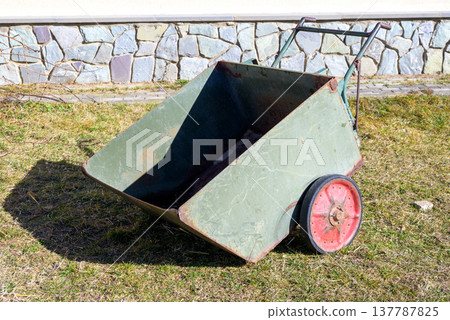 Vintage metal garden cart with red wheels on grass 137787825