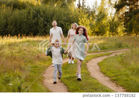 Bright Family Dash Across Verdant Meadow With Children At Forefront And Parents Playing Along Bright Family Dash Across Verdant Meadow With Children At Forefront And Parents Playing Along 137788182