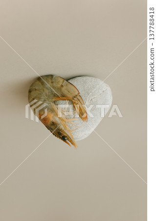 Shrimp and stone in the shape of a heart on a beige background. 137788418