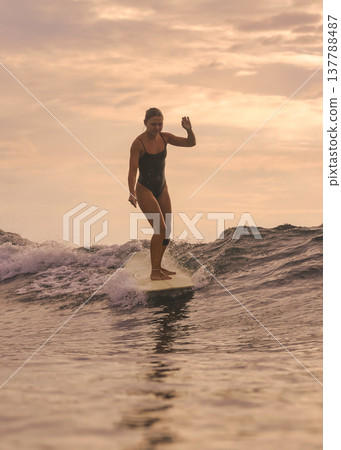 Cheerful Woman Engaging In Playful Surfing Beneath Bright And Sunny Sky Cheerful Woman Engaging In Playful Surfing Beneath Bright And Sunny Sky 137788487