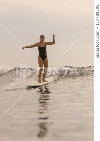 Gracious Lady Maintains Perfect Balance On Her Longboard Beneath Setting Sun 137788505