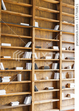 Tall wooden bookshelves with minimal decor and books in modern loft library, office, study interior Tall wooden bookshelves with minimal decor and books in modern loft library, office, study interior 137788621