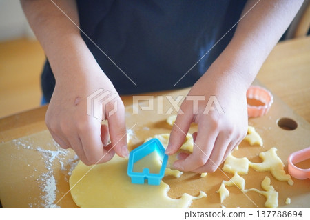 A scene of a child making sweets, using cookie cutters to cut out shapes from dough. 137788694