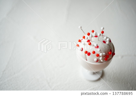 一張特寫照片，展示了一個插滿紅色和白色圖釘的針墊。 137788695